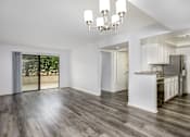 Thumbnail 29 of 53 - A spacious kitchen and living room with wooden floors and white walls.