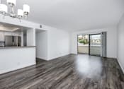 Thumbnail 15 of 53 - A large empty room with wooden floors and a kitchen area to the left.