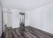 Thumbnail 23 of 53 - A room with white walls and wood flooring with a doorway leading to another room.