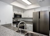 Thumbnail 19 of 53 - A kitchen with a granite counter top and stainless steel appliances.