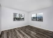 Thumbnail 45 of 53 - A room with wooden floors and two windows with blinds.