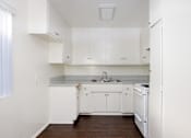 Thumbnail 26 of 28 - a kitchen with white cabinets and white appliances and a wood floor