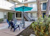 Thumbnail 6 of 28 - a patio with chairs and an umbrella in front of a building