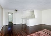 Thumbnail 19 of 28 - an empty living room and kitchen with hardwood floors and a ceiling fan