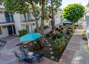 Thumbnail 7 of 28 - a courtyard with a blue umbrella and tables and chairs