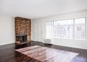 Thumbnail 20 of 28 - an empty living room with a brick fireplace and hard wood floors