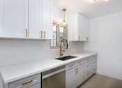 Thumbnail 24 of 41 - a kitchen with white cabinets and a sink and a gold faucet