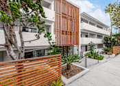 Thumbnail 1 of 63 - A modern building with a wooden fence and plants in front.