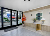 Thumbnail 29 of 63 - A hallway with a gold console table and a vase of orange flowers.