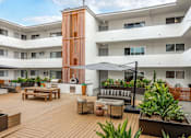 Thumbnail 31 of 63 - A modern building with a wooden deck and furniture.