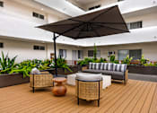 Thumbnail 36 of 63 - A patio with a wicker chair and a large umbrella.
