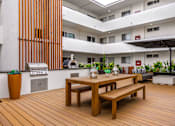 Thumbnail 37 of 63 - A wooden table and bench are in the foreground of a modern patio area.