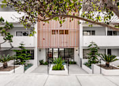 Thumbnail 4 of 63 - A modern house with a white exterior and a wooden slat wall on the front.