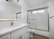 Thumbnail 57 of 63 - A white bathroom with a sink, mirror, and toilet.