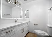 Thumbnail 59 of 63 - A white bathroom with a toilet, sink, and mirror.
