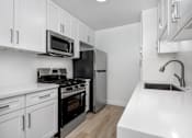 Thumbnail 62 of 63 - A kitchen with white cabinets and black appliances.
