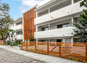 Thumbnail 6 of 63 - A modern building with a white facade and a wooden fence.