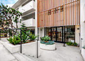 Thumbnail 7 of 63 - A modern building with a white and orange facade and a small garden in front.
