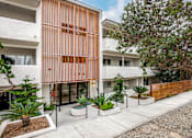 Thumbnail 8 of 63 - A modern building with a white and orange facade and a gravel driveway in front.