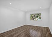 Thumbnail 20 of 52 - A room with wooden flooring and a window with a view of trees.