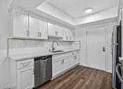 Thumbnail 9 of 52 - A kitchen with white cabinets and a wooden floor.