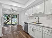 Thumbnail 26 of 52 - A modern kitchen with white cabinets and a wooden floor.