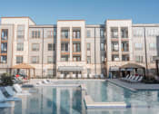 Thumbnail 3 of 17 - College Station, TX Apartments - Exterior View of Caprock Crossing Apartments Building Surrounded By Lush Landscaping with View of Outdoor Lounge