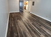Thumbnail 15 of 29 - A room with wooden flooring and a door leading to another room.