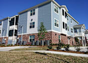 Thumbnail 1 of 22 - A blue and white apartment building with a brick base.