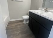 Thumbnail 26 of 29 - A bathroom with a toilet, sink, and a mirror.