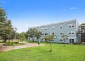 Thumbnail 1 of 4 - A large building with a green lawn in front.