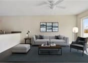 Thumbnail 2 of 4 - A living room with a grey couch, a black chair, and a white lamp.