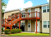 Thumbnail 9 of 10 - A tan and white two story apartment building with a red staircase.
