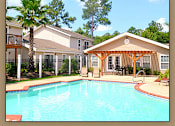 Thumbnail 2 of 10 - A pool in front of a house with a patio.