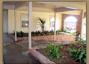 Thumbnail 2 of 7 - A patio with a brick wall and plants.