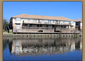 Thumbnail 5 of 7 - A building is situated on a dock over water.