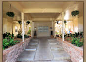 Thumbnail 6 of 7 - A covered walkway with a stone path and plants on either side.