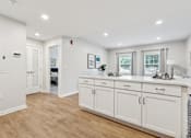 Thumbnail 3 of 18 - A white kitchen with wood floors and white cabinets at Roosevelt Commons Apartments, Pennsylvania 19152