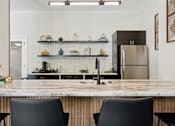 Thumbnail 41 of 57 - A modern kitchen with a marble countertop and black chairs.