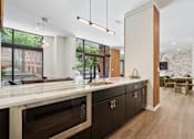 Thumbnail 42 of 57 - A modern kitchen with dark wood cabinets and a marble countertop.