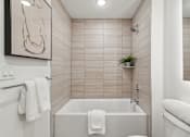 Thumbnail 27 of 57 - A white bathroom with a tub and a towel hanging on the side.