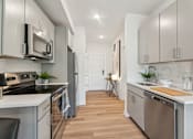 Thumbnail 22 of 57 - A modern kitchen with stainless steel appliances and wooden floors.