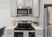 Thumbnail 23 of 57 - A modern kitchen with a stove, microwave, and refrigerator.