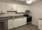 Thumbnail 9 of 20 - a kitchen with white cabinets and black appliances and a ceiling fan