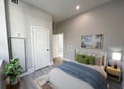 Thumbnail 16 of 37 - A bedroom with a bed, nightstand, and a painting on the wall.