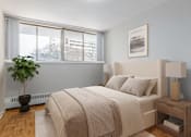 Thumbnail 7 of 12 - A bedroom with a large bed and a potted plant.