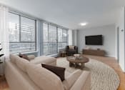 Thumbnail 3 of 12 - A living room with a large couch, a coffee table, and a flat screen TV.