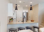 Thumbnail 4 of 15 - A kitchen with a white counter top and a stainless steel refrigerator.