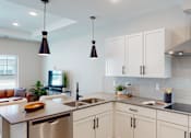 Thumbnail 5 of 15 - A modern kitchen with white cabinets and a stainless steel sink.