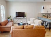 Thumbnail 7 of 15 - A living room with a television, couches, and a bar area.